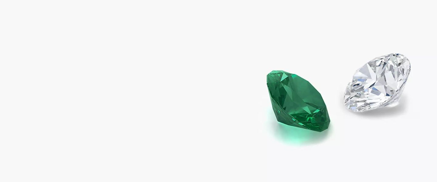 A loose emerald gemstone faces to the left across from a loose diamond gemstone facing to the right